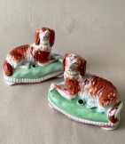 Pair of Staffs dog inkwells, Two opposed recumbent Spaniels on green cushions